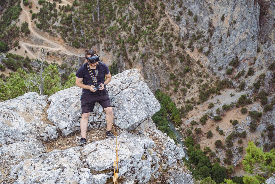 Man with VR headset on a rocky cliffside in Göksun Canyon, Türkiye, experiencing virtual reality outdoors.